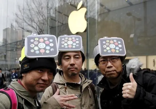Men wearing cardboard hats depicting the Apple Watch, pose for photos before it goes on display in front of the Apple Store in Tokyo's Omotesando shopping district April 10, 2015. REUTERS/Toru Hanai